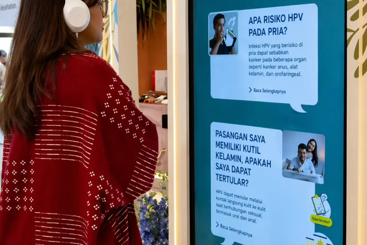 Couples watching HPV awareness video with shared headset at ngobrolinhpv.com event