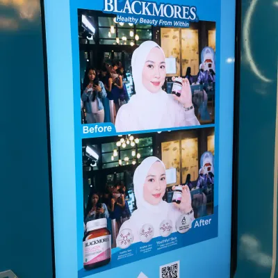 Blackmores AI beauty photobooth screen displaying a hijab guest portrait with before and after product-inspired transformation