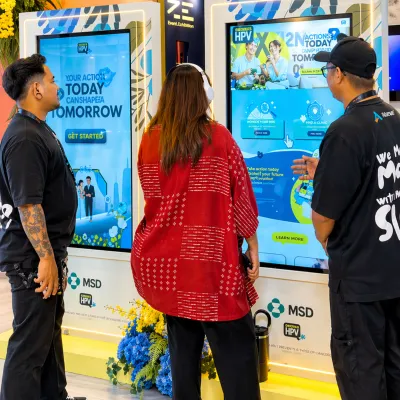 HPV awareness video experience booth for ngobrolinhpv.com with visitors using a touchscreen display at an event activation