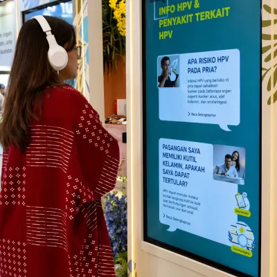 Event visitor using a headset to watch the HPV awareness educational video experience on an interactive digital information display
