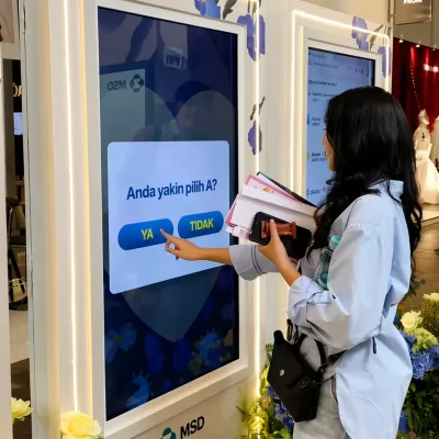 Participant using a touchscreen educational quiz web app inside the MSD HPV event activation booth during an interactive health awareness experience