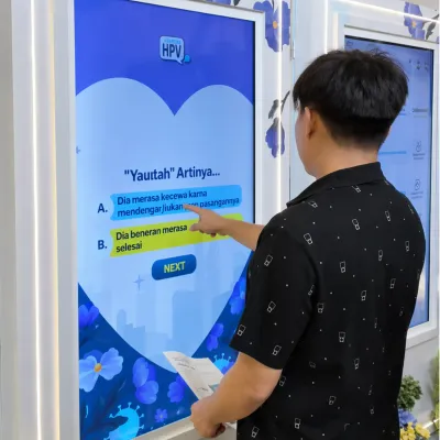Participant playing the MSD HPV touchscreen quiz game with multiple choice questions during a branded educational event activation