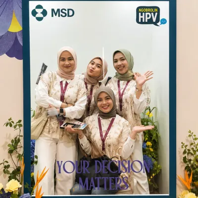 Visitors posing inside a branded MSD HPV photo booth frame as part of an interactive health education event experience