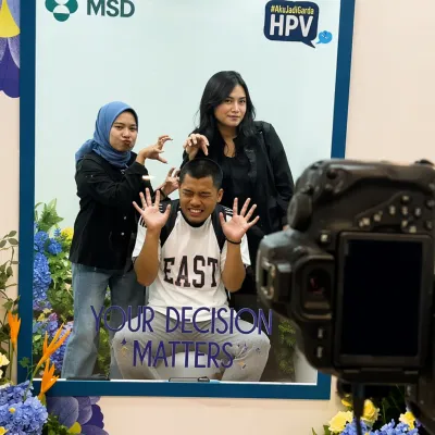 Group photo session inside the MSD HPV activation booth with camera setup capturing the live branded event experience