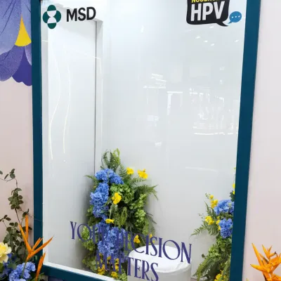 Empty MSD HPV branded photo frame installation with floral decorations prepared for participant photo sessions at the event booth