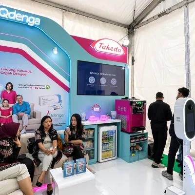 Takeda Qdenga campaign booth with interactive touchscreen presentation hub for event product communication in Malang