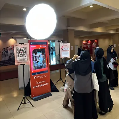 Visitors using an interactive CIMB Niaga Syariah digital signage photobooth at Hayafest, combining promo awareness content with an on-site photo experience