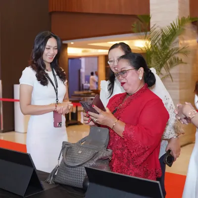 Event crew assisting a guest during the on-site digital registration process for Poppy Gunadi 80th birthday celebration